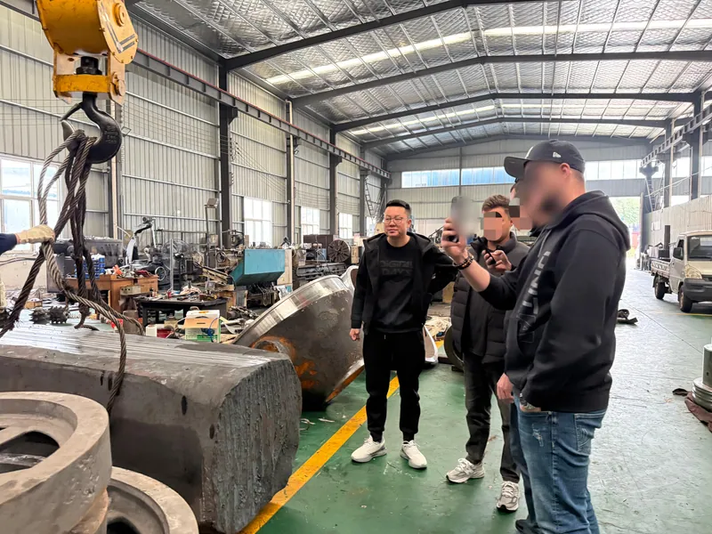 A crane hook and slings above a large cast block while a customer photographs it.