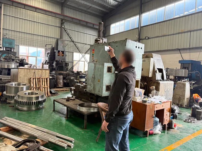A customer photographing a vertical gear shaper, with finished gear rings on the floor beside it.