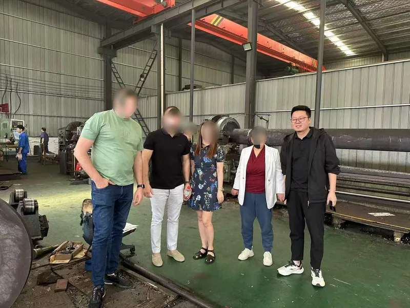Visiting customers and Linyao colleagues standing in a row under the workshop crane.