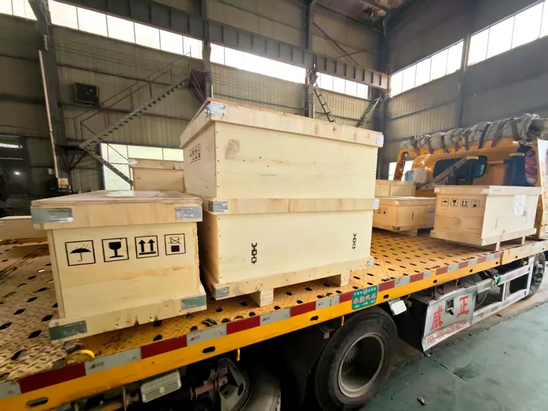 Export plywood cases with keep-dry, fragile, this-way-up and no-hooks marks, braced with steel corners and strapped on a flatbed truck.